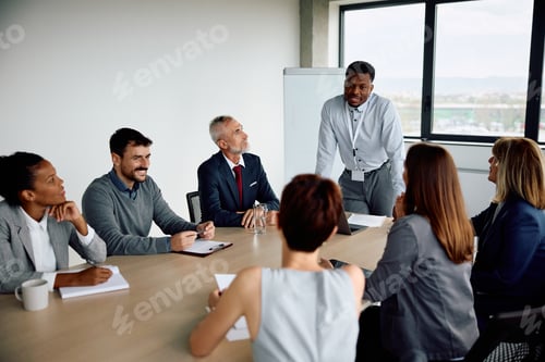 Preview: Black businessman talking to group of colleagues during a meeting in the office.
