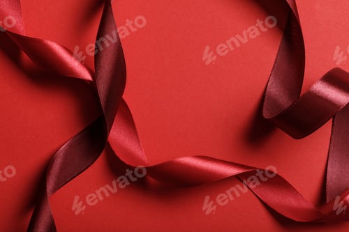 Preview: close up of curved silk burgundy and red ribbons on red background