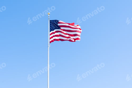 Preview: American flag waving in the wind against blue sky