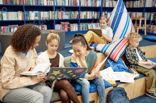 Preview: Two Girls using Laptop in Library with Teacher Helping