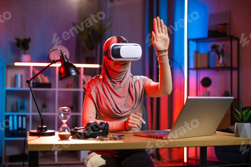 Preview: Arabian woman using VR headset and laptop for work at home