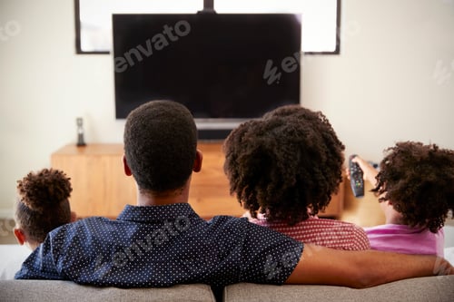 Preview: Rear View Of Family With Children Sitting On Sofa Watching TV Together