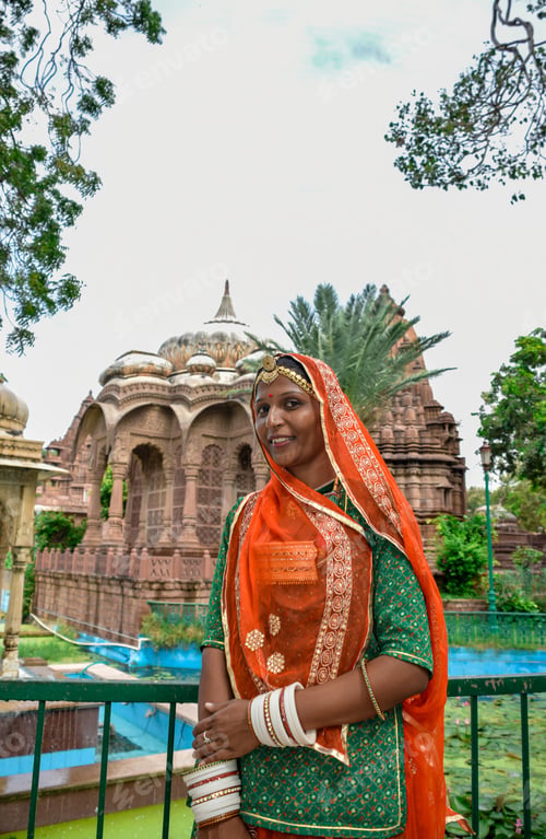 Preview: Indian Woman with beautiful face and orange sari posing with ruins in background