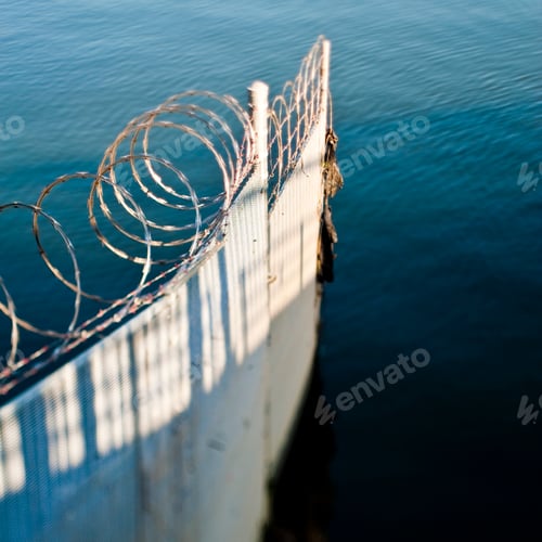 Preview: Corrugated iron fence and barbed wire in ocean.