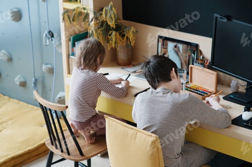 Preview: Two boys drawing at home during lockdown, using online lesson on laptop. Online education