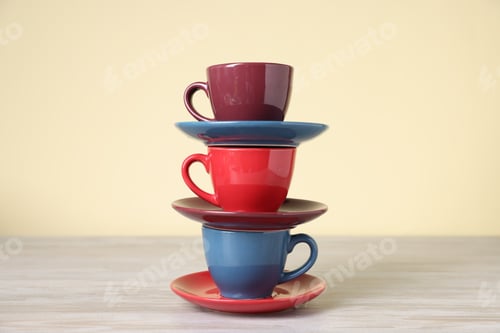 Preview: Beautiful cups and saucers on light wooden table against beige background