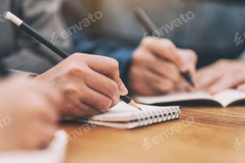Preview: Closeup image of many people writing on blank notebook together on wooden table