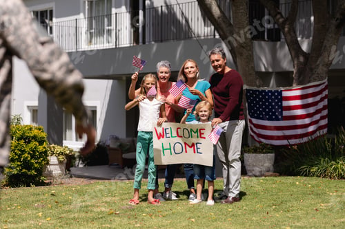 Preview: Caucasian soldier father and family meeting outside home with welcome sign and american flags