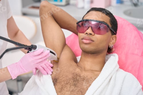 Preview: Young man undergoing laser epilation procedure in beauty clinic