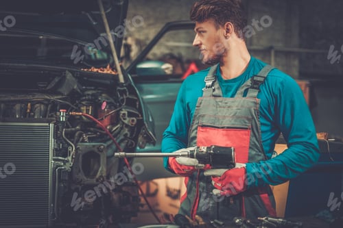 Mechanic with pneumatic tool in a workshop