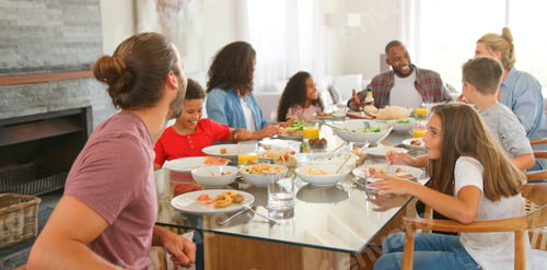 Preview: Two Families Sitting Around Table Together Enjoying Meal At Home