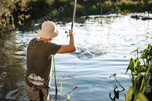 Preview: Young fisherman with fishing rod near the lake at summer