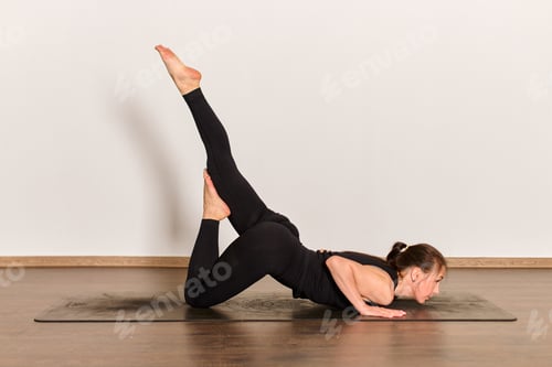 Preview: Woman in peacock feather pose on yoga mat indoors