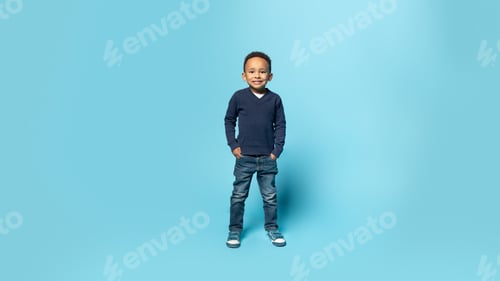 Preview: Happy childhood. Full length shot of black little boy holding hands in pockets, blue background