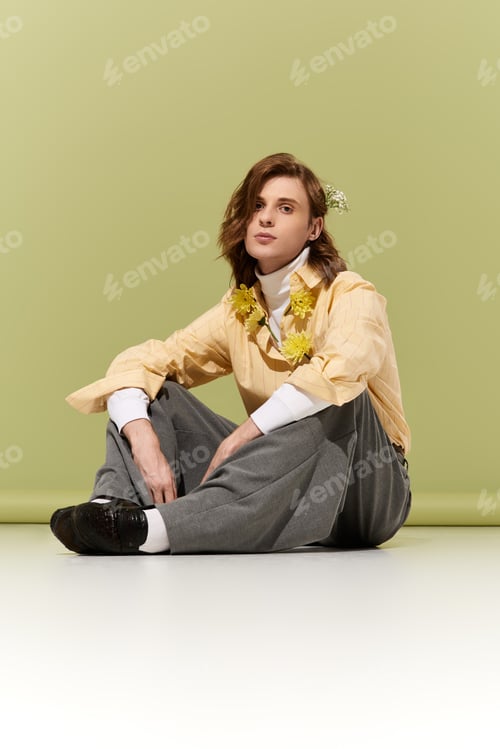 Preview: Young man showcases modern fashion with floral accents against a soft green backdrop