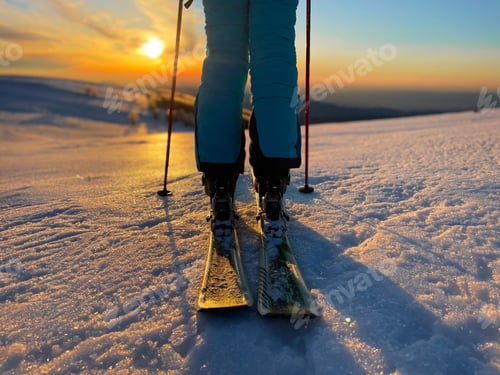 Skier Standing on Snowy Mountain at Sunrise