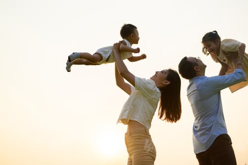 Preview: Happy father and mother holding children playing together in park