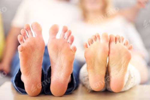 Preview: Barefeet of a happy couple lying on a sofa