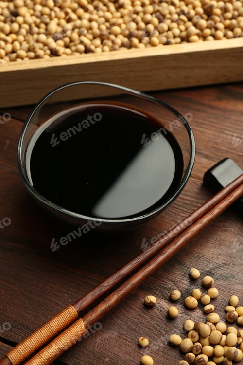 Preview: Soy sauce in bowl, soybeans and chopsticks on wooden table