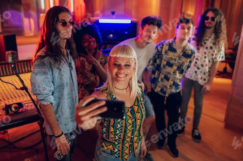 Preview: Multiracial band members taking a selfi with a smartphone in a music studio
