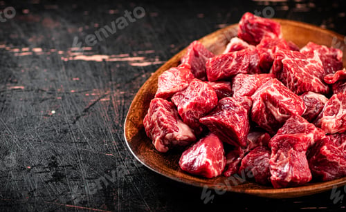 Preview: Chunks of fresh raw beef on a plate.