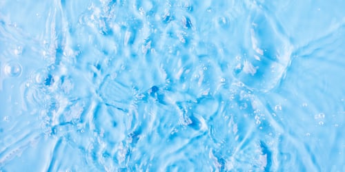 Preview: Rippling water surface and droplet on blue background close view from above