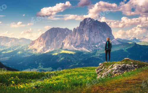 Preview: Girl on the peak, flowers and green grass in alpine mountains