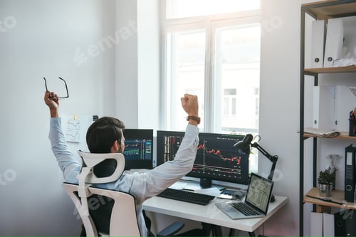 Preview: Winner Back view of stock trader with raised hands holding eyeglasses and feeling happy while