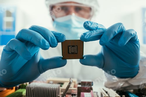 Preview: selective focus of engineer holding microchip near computer motherboard