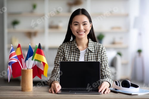 Preview: Cheerful asian woman showing laptop with blank screen