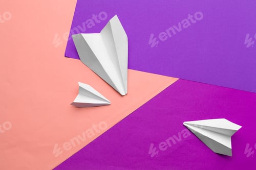 Preview: white paper airplane on a color block paper background