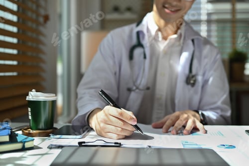 Preview: Cropped shot of smiling doctor wearing white uniform sitting bright office and filling medical form.