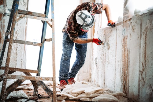 Preview: Construction worker removing spray foam on the walls of a building