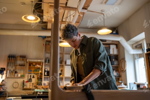 Preview: Concentrated carpenter working on making a table, using clamping brackets and bar clamps. Woodwork.