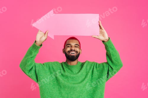 Preview: Joyful african american guy smiling and showing arrow placard