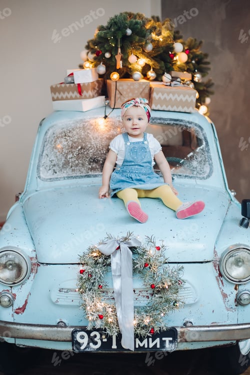 Preview: Front view of sweet and fashionable little cute girl sitting on blue retro car decorated for