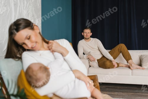 Preview: Baby Son Sucks Milk from the Mother's Breast, the Happy Father Watches Them. Portrait of Mom