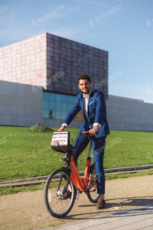 Preview: Portrait of smiling hispanic businessman riding a bike. Full view, copy space.