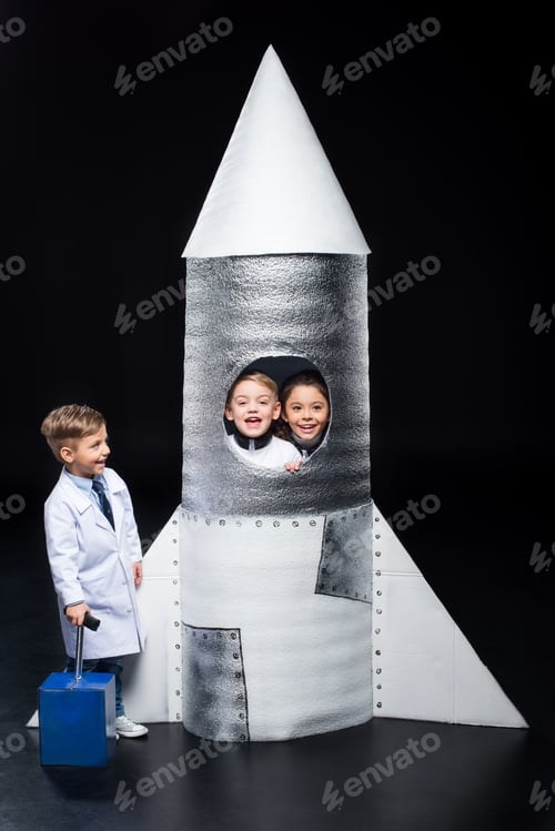 Preview: Three smiling little kids playing astronauts with spaceship on black