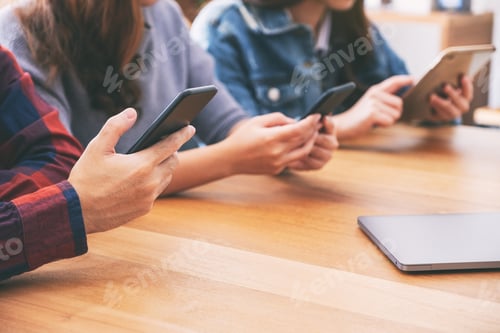 Preview: Three young asian people using and looking at mobile phone and tablet pc