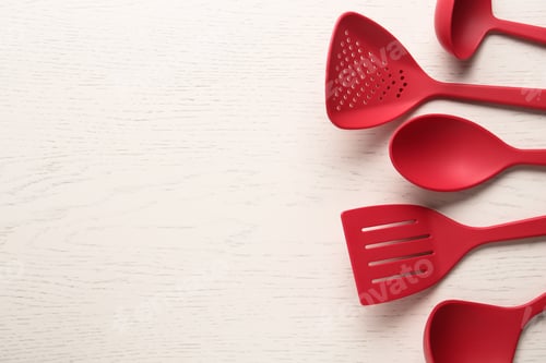 Preview: Set of red cooking utensils on white wooden table, flat lay. Space for text