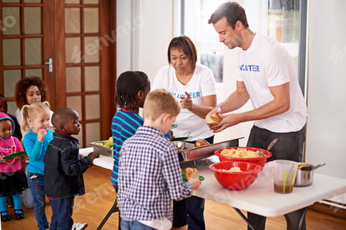 Preview: Theres plenty for everyone. Shot of volunteers serving food to a group of little children.