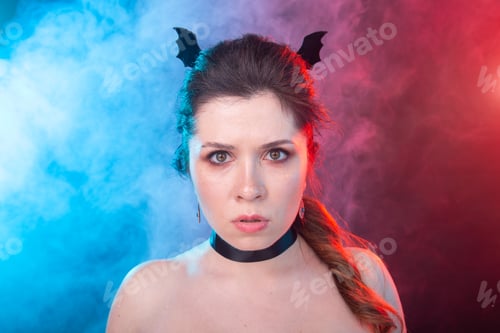 Preview: Dark fashion, halloween and people concept - gothic woman in bat ears over the dark background