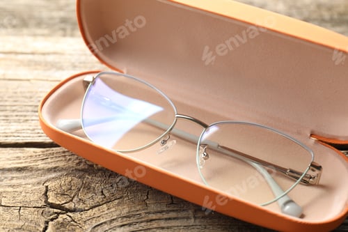 Preview: Stylish glasses in case on wooden table, closeup