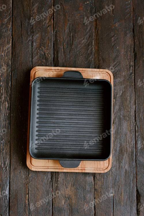 Preview: New empty cast-iron grill pan with two handles on wooden background