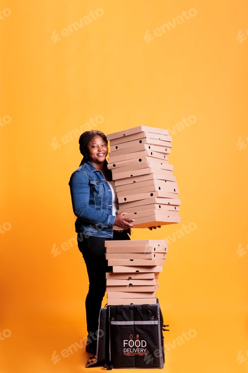 Preview: Smiling deliverywoman holding stack full of pizza boxes preparing to deliver to clients