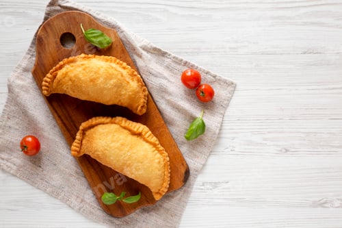 Preview: Homemade Deep Fried Italian Panzerotti Calzone on a rustic wooden board on a white wooden table