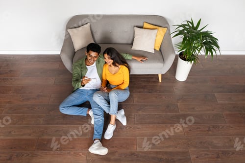 Preview: Hindu spouses engaging in phone at home, above view, copy space