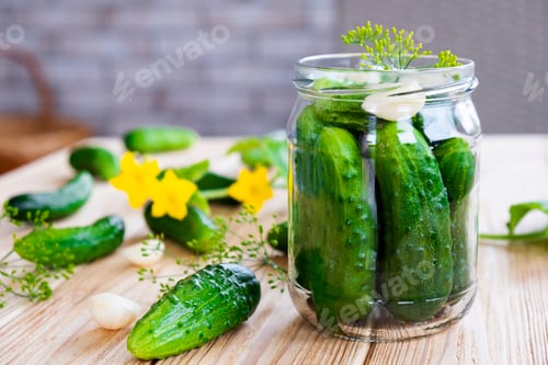 Preview: Glass jar with fresh cucumbers, herbs, garlic and dill on wooden board.