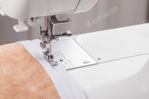 Preview: Modern sewing machine special presser foot with beige fabric and zipper, closeup